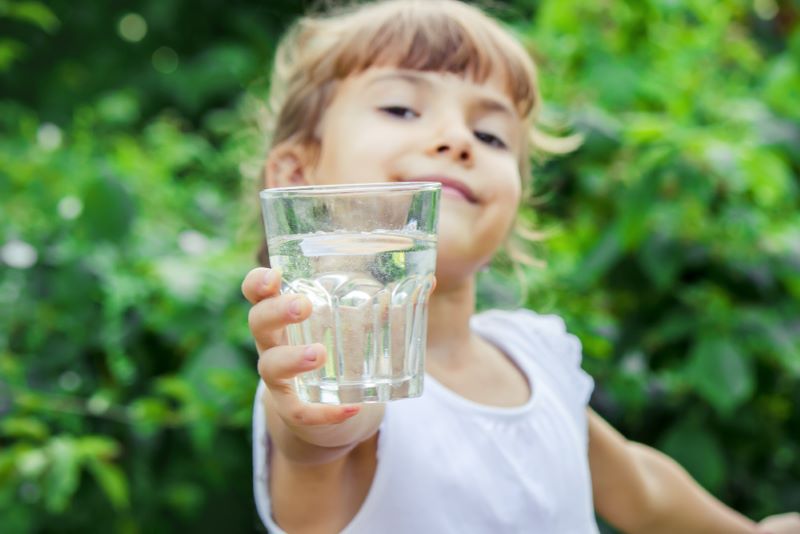 Une fillette de six ans tend un verre d'eau au photographe