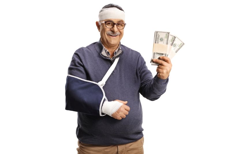Un homme âgé dont le bras est cassé, montre une liasse de billets de banque liés au remboursement de sa mutuelle santé Kovers