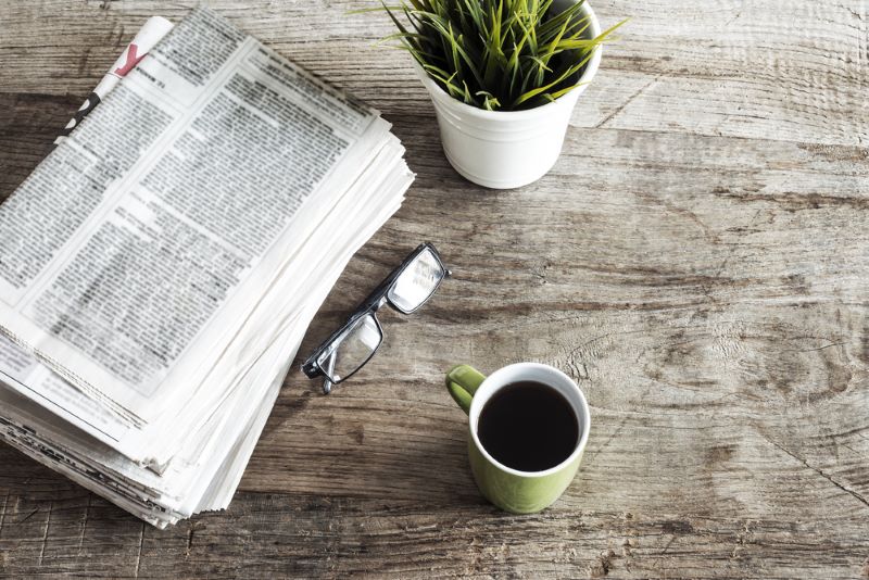 Un journal La Provence posé sur une table à côté d'une paire de lunettes et d'un café