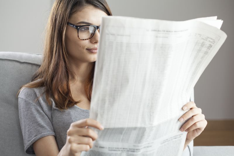Une femme assise porte des lunettes pour lire les actualités du journal Le Parisien