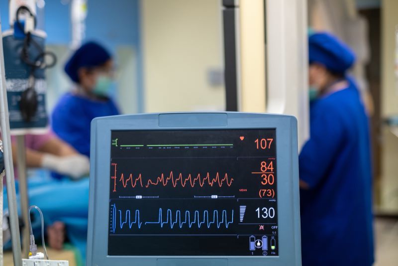 Un électrocardiogramme montre les battements du cœur d'un patient avec, en arrière plan, deux soignants qui échangent
