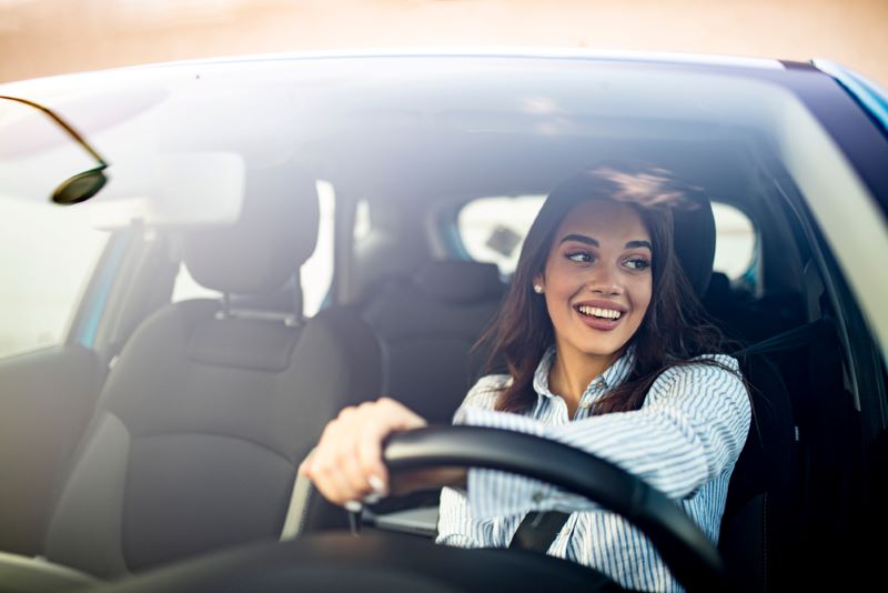 Une jeune femme est au volant d'une voiture, louée par le biais de OuiCar