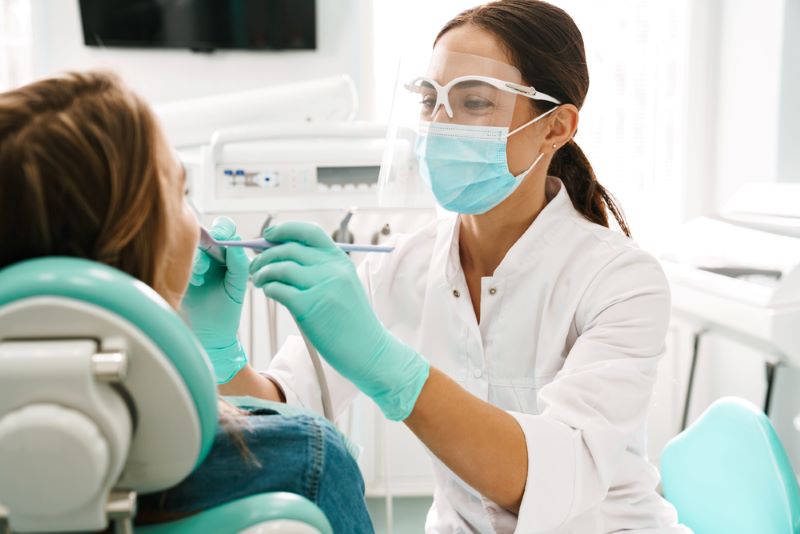 Une dentiste regarde dans la bouche de son patient pour commencer les soins