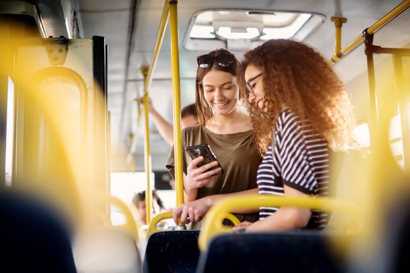 Deux jeunes filles sont dans le bus et regardent leur portable en attendant d'atteindre leur destination