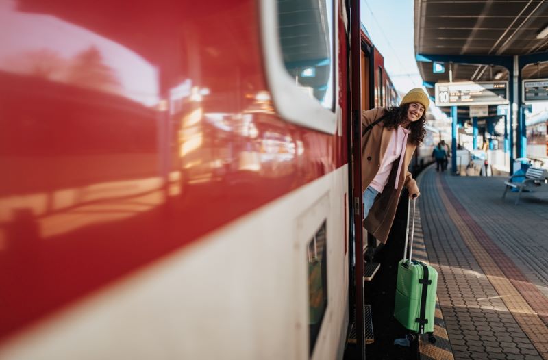 Une jeune femme se penche du train avant que le départ ne soit donné par le chef de gare