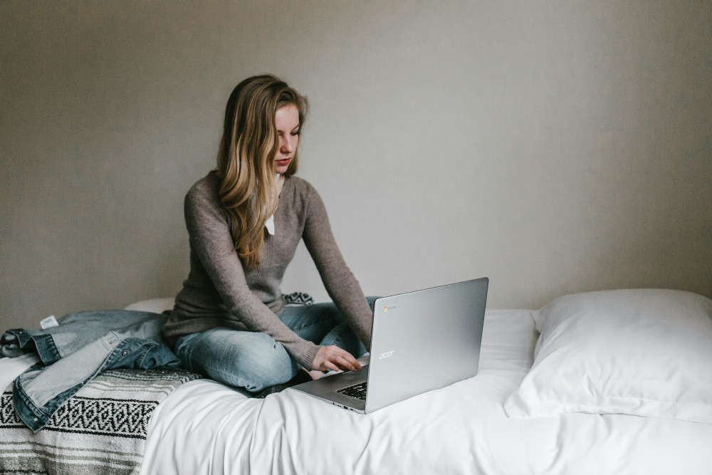 femme blonde, assise sur un lit, résiliant son abonnement HBO Max depuis son PC portable