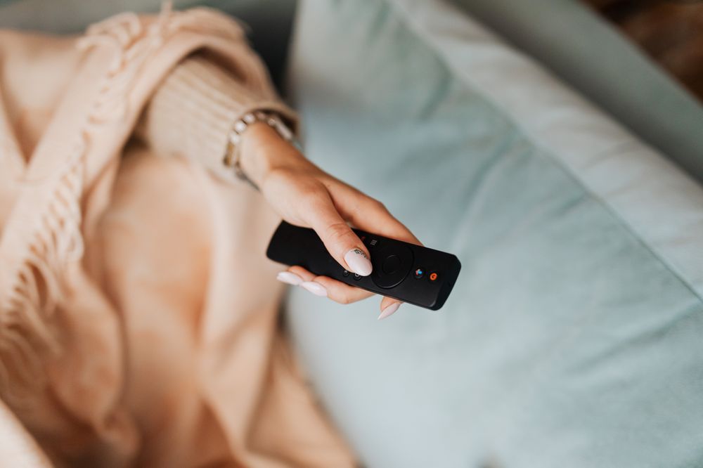 femme résiliant SFR TV avec une télécommande via son décodeur