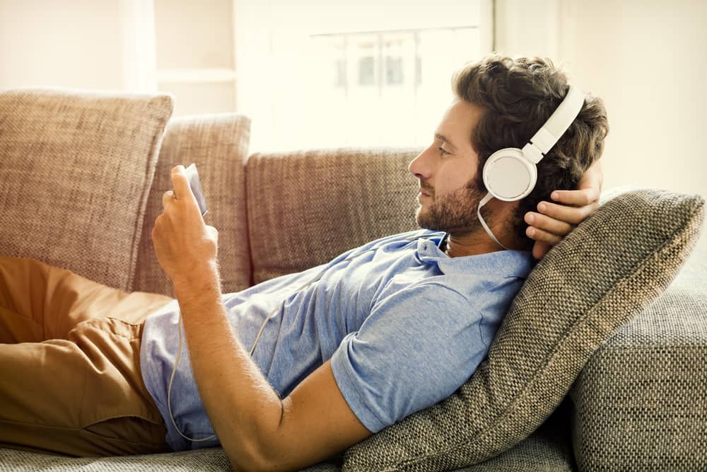 homme allongé sur son canapé écoutant de la musique sur Spotify