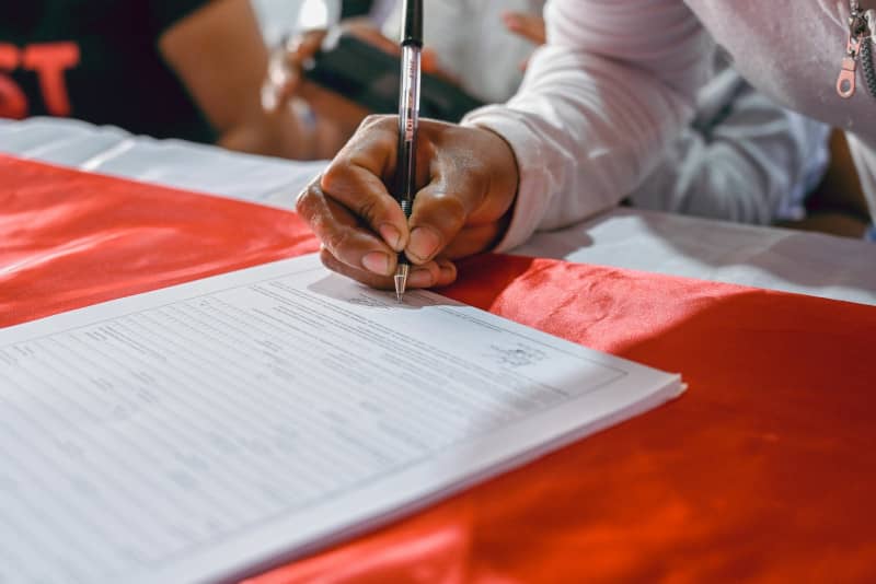 main d'une personne signant une lettre de résiliation pour un contrat accidents de la vie Pacifica