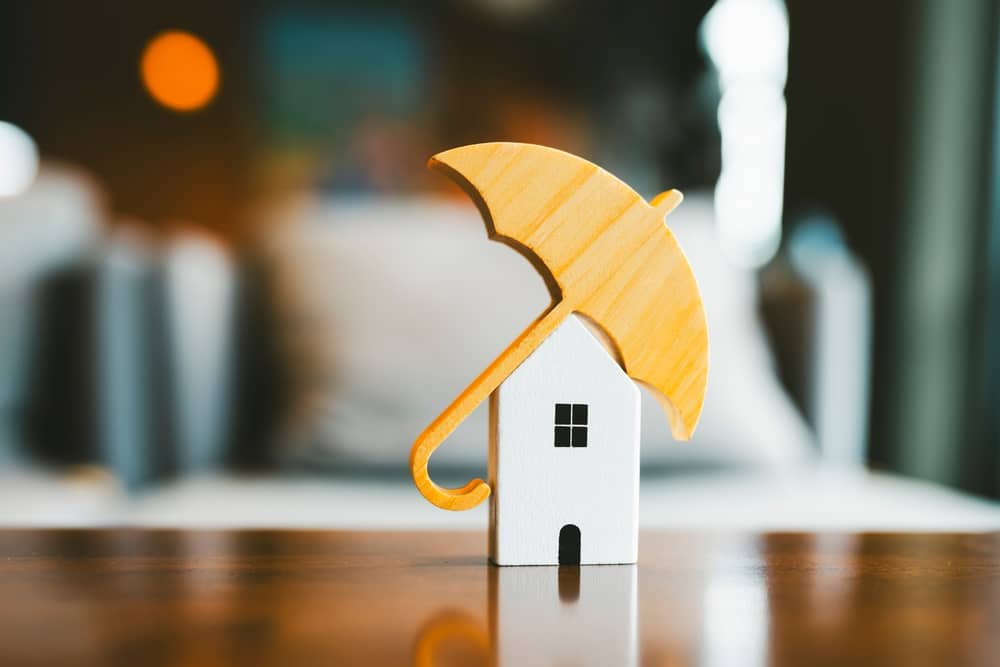 petite maison blanche couverte par un parapluie, pour représenter l'assurance habitation de Cardif
