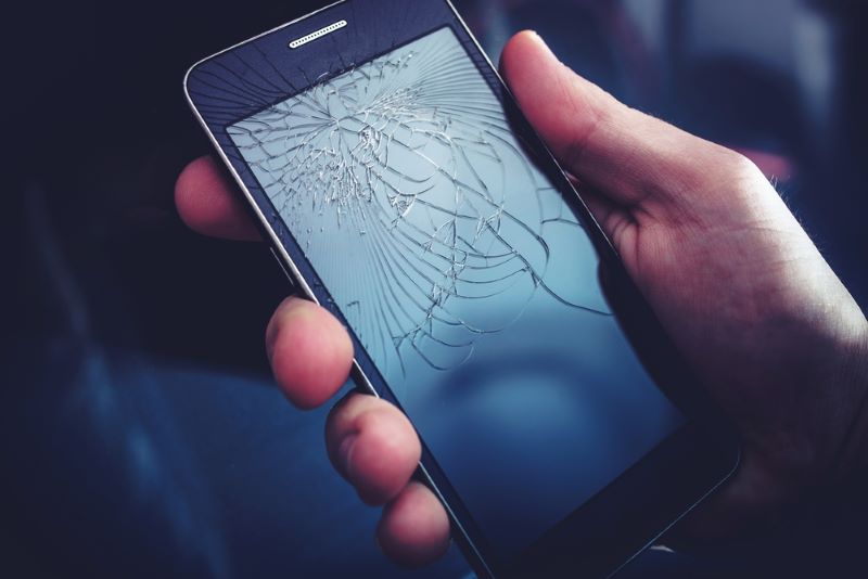 Un smartphone dont l'écran est cassé suite à une chute sur le trottoir