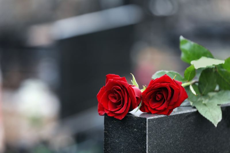 Des roses rouges, posées sur une pierre tombale. 