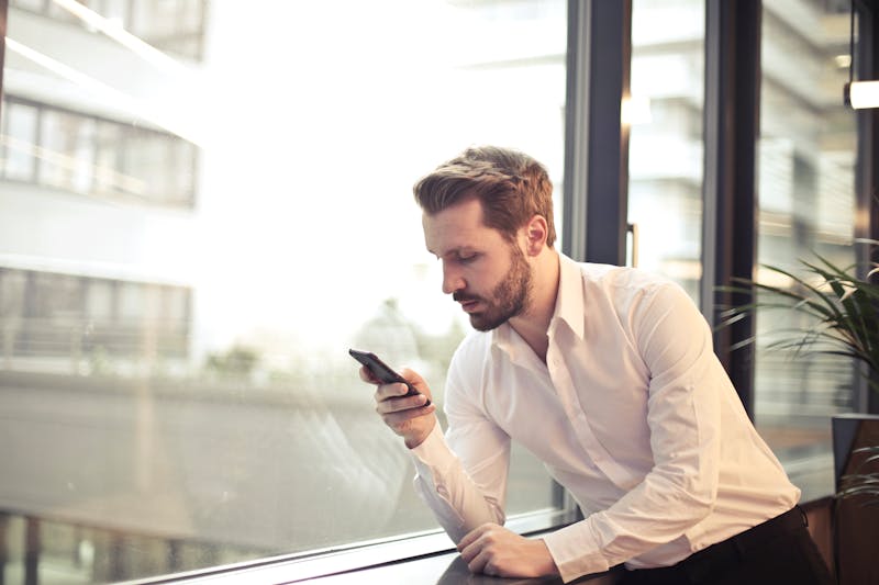 homme blond utilisant son smartphone protégé par l'assurance GSM d'ATM