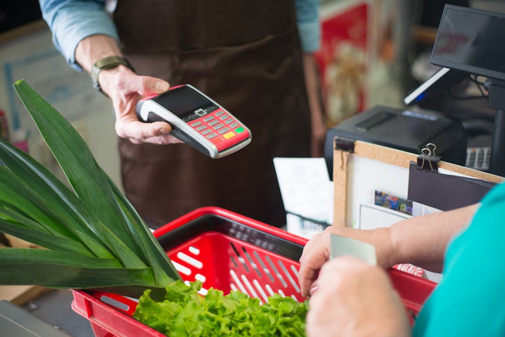 client s'apprêtant à passer sa carte de fidélité Leclerc à la caisse d'un magasin