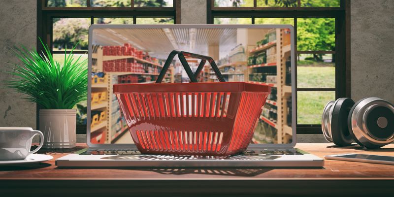 Un panier posé sur un ordinateur dont l'écran montre un supermarché symbolise l'e-commerce actuel