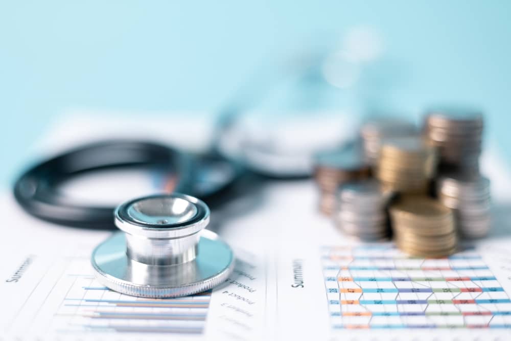 contrat de mutuelle CNP posée sous un stéthoscope et des pièces de monnaie