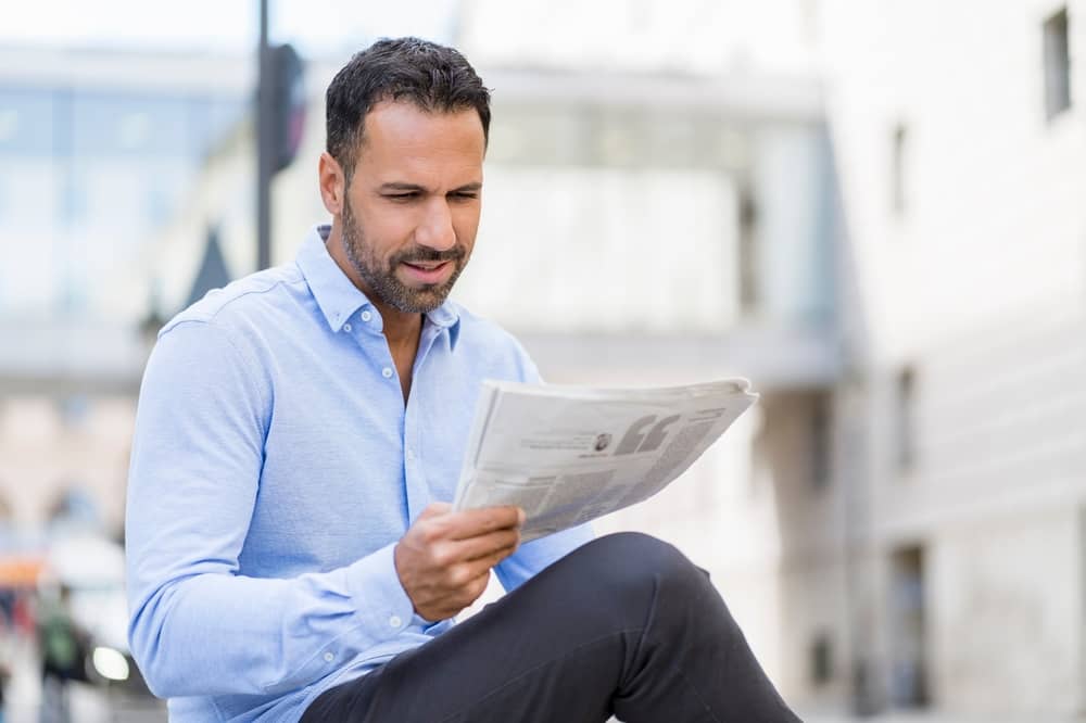 homme en train de lire un numéro du journal L’Équipe