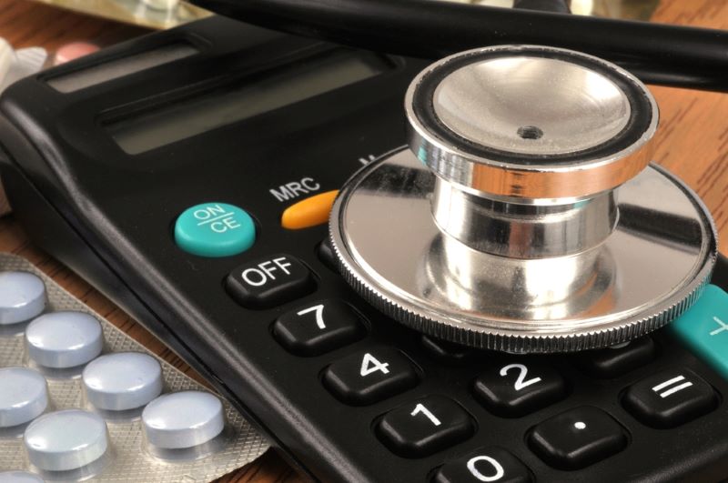 Un stéthoscope posé sur une calculatrice symbolise le coût actuel des soins