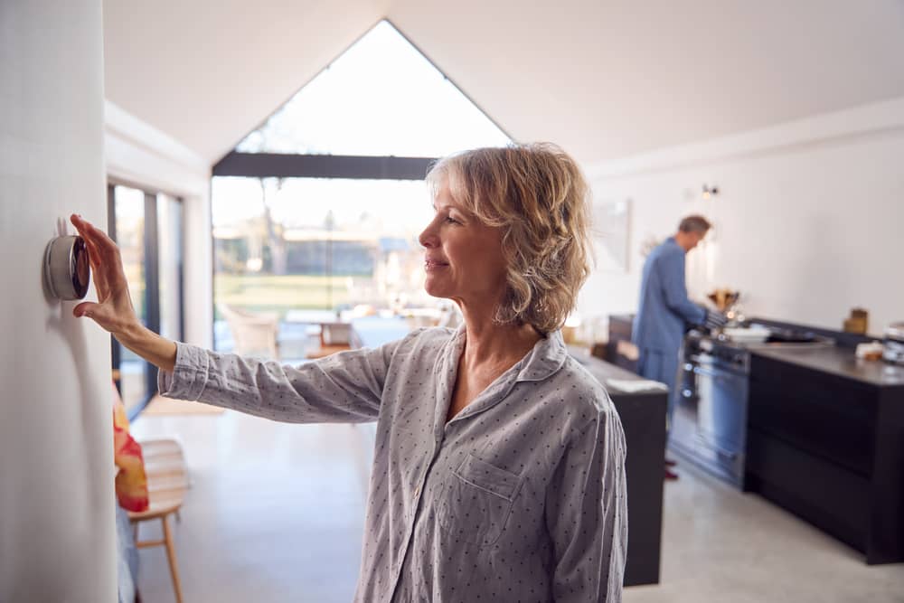 femme réglant son thermostat OHM Énergie