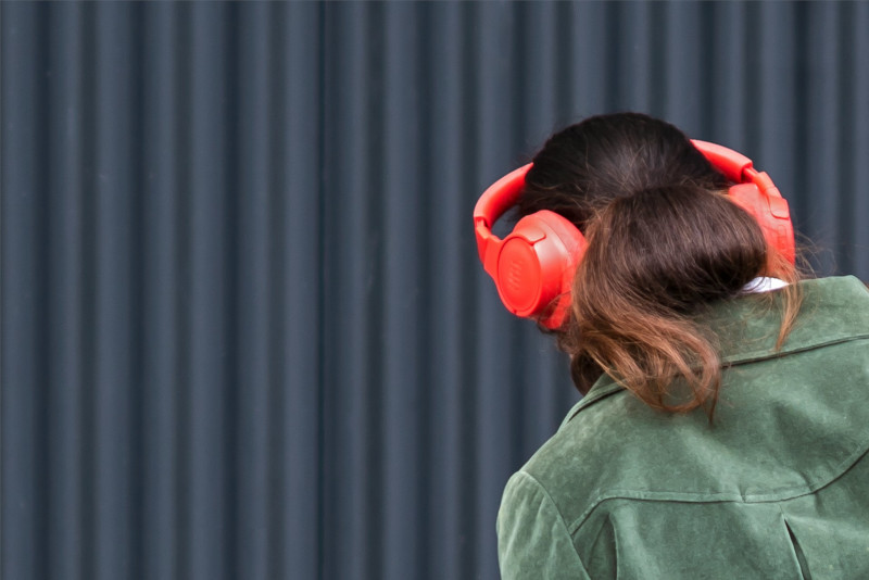 jeune femme de dos, avec un casque orange sur la tête, écoutant de la musique sur Soundcloud