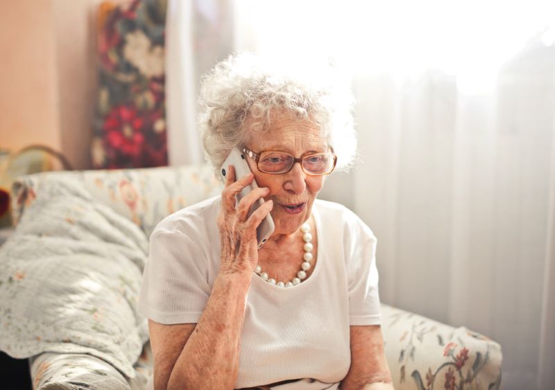 Dame âgée qui reçoit un appel, assise dans sa salle à manger